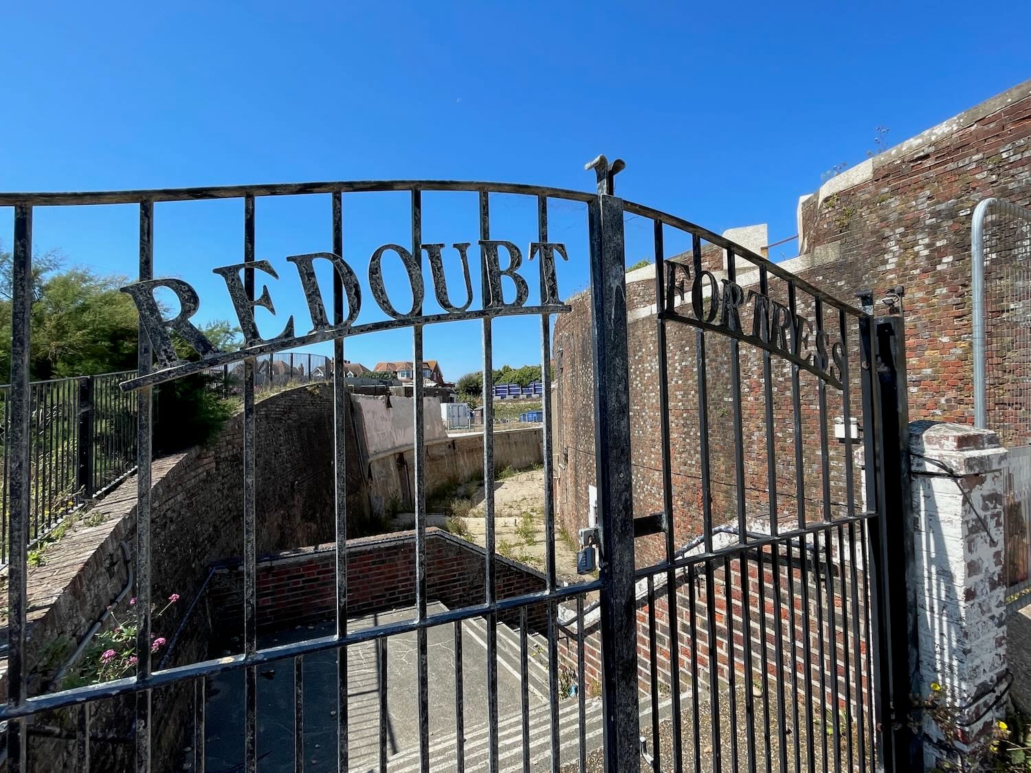 Closed iron gates with the words Redoubt Fortress across them and descending steps behind